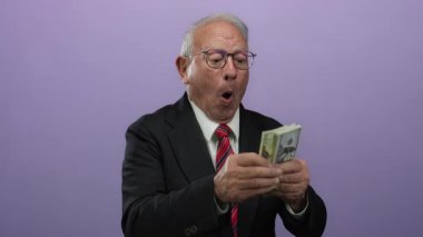 Üst düzey bir adam bize dolar banknotları sayarak mor bir arka plan, sergilenen iş başarısı ve finansal bolluk karşısında.