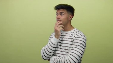 Sarı arka plan üzerinde düşünceli bir genç, çizgili bir gömlek giyiyor, içsel ve ilginç bir tavır sergiliyor..