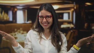 Restoran yemek alanında el dürbünüyle el hareketleriyle yüzünü çerçeveleyen genç kadın, merakı araştırıyor..