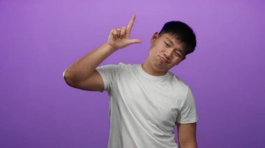 Beyaz gömlekli genç adam, izole edilmiş mor arka plana el hareketi yapıyor. Duygularını neşeli bir şekilde ifade ediyor..