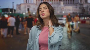 Pembe gömlekli ve kot ceketli bir kadın gecenin bir yarısı işlek bir caddede dikiliyor. Işıklardan ve bulanık binalardan oluşan bir kalabalığın arasında bitkin hissediyor..