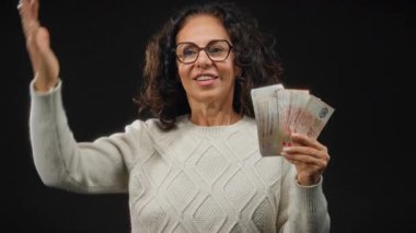 Siyah bir arkaplan karşısında elinde Singapur doları tutan orta yaşlı bir kadın tatmin olmuş görünüyor..