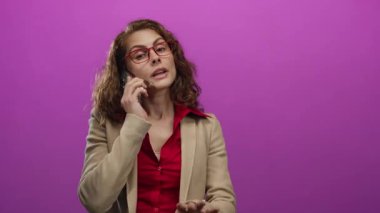 Pembe arka planda telefonla konuşan, gözlüklü ve spor ceketli bir kadın, canlı sohbete kişilik ve profesyonellik katıyor..