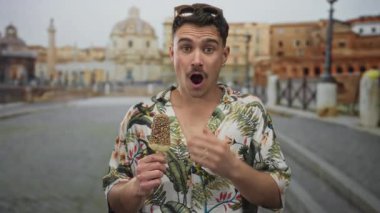 Çiçekli tişörtlü genç İspanyol adam elinde dondurma, güneşli bir günde Roma harabelerinin önünde şaşırmış, gezintiler ve açık hava eğlencesi sergiliyor..