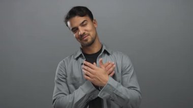 Gri bir arka planda poz veren İspanyol genç adam hareketlerini ve yüz ifadelerini gösteriyor. Kendine güvenen ve hoş karşılayan titreşimleri yakalıyor..