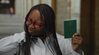 Şehir caddesinde Suudi pasaportu taşıyan bir kadın açık havada düşünceli bir ifadeyle seyahat ve uluslararası çeşitliliği gösteriyor..