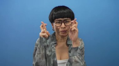 Umut dolu yüzüyle umut dolu parmaklar üzerinde duran zarif gözlük ve küpeler takan bir kadın.