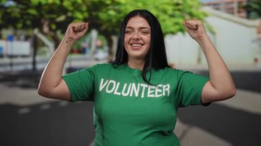 Şehir caddesinde kendine güvenen, açık havada yeşil tişört giyen, genç kadınlarda güç ve çeşitliliği temsil eden gönüllü bir kadın..