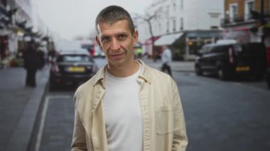 Arka planda bulanık arabaları ve binaları olan kalabalık bir sokakta duran bir adam, araçlar ve yayaların bulunduğu bir şehir ortamında şehir yaşam tarzını gözler önüne seriyor..