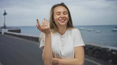 Sahilde sırıtan bir kadın, arka planda suyla birlikte keyifli bir günde açık deniz manzarasının keyfini çıkarıyor..