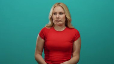 Kırmızı gömlekli, sarı saçlı bir kadın mavi arka plana karşı duruyor. Kafa karışıklığı ve belirsizliği ifade ediyor. Etkileyici tavırlarıyla dinamik bir görsel birliktelik yaratıyor..