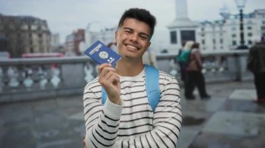 Şehir sokaklarında elinde Kore pasaportuyla gülümseyen bir adam bulanık şehir geçmişi olan, çizgili gömlek ve mavi sırt çantası giyen seyahat ve turizmi ön plana çıkaran bir adam..