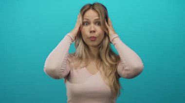 Avuç içleri kalkmış sarışın kadın stüdyoda omuz silkme hareketi gösteriyor. Şaşırtıcı kafa karıştırıcı belirsizlik..