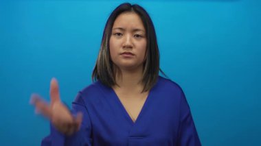 Stüdyo ortamında gücünü ve duygularını ön plana çıkaran sert mavi arka planda kararlı bir kadın görülüyor..