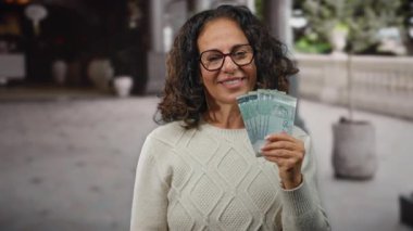 Malezya 'da şehir caddesinde gülümseyen orta yaşlı bir kadın halka banknotlar tutuyor..