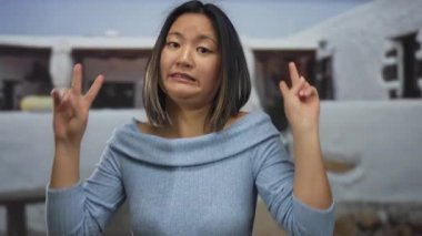 Kentsel sokaktaki genç kadın açık havada jest yapıyor. Şehir ortamında mizah ve sürpriz öneriyor.