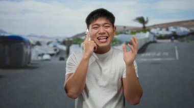 Şehir sokaklarında telefonla konuşan genç bir adam, etkileyici bir tavırla, canlı bir metropol ortamında iletişim ve şehir yaşamını vurguluyor..