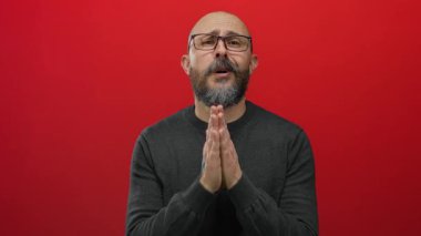 Kel, sakallı ve gözlüklü bir adam koyu renk bir süveter giyer ve stüdyoya kapanır..