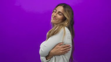 Genç sarışın kadın mor fotoğraf stüdyosunda omuzlarını nazikçe tutuyor..