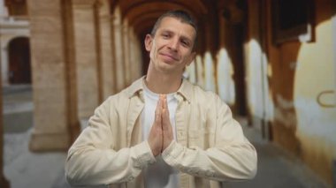 Açık hava üniversitesinde dua eden bir adam yumuşak ışıkla yıkanmış antik mimari ile yansıma ve huzur öneriyor..