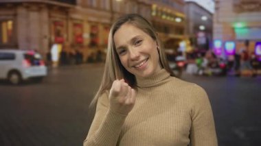 Sokakta parmakla işaret eden genç sarışın kadın; davet sıcaklığı.