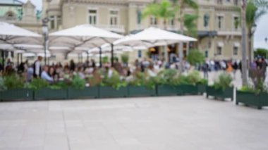Monaco 'da, bulanık insanların şemsiyeler altında kentsel manzaranın tadını çıkardığı, dağınık, lüks bir sokak sahnesinin olduğu açık hava görüntüsü..