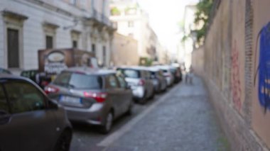 Roma 'daki bulanık kaldırım taşı caddesi. Park etmiş arabalar eski kasaba yolunu aydınlık gün ışığında kaplıyor..