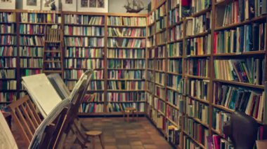 Kitap raflarının renkli kitaplarla dolu olduğu bulanık kütüphane sahnesi ve kapalı bir atmosfer, okumak ve öğrenmek için mükemmel sessiz bir köşe.