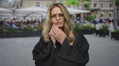 Dışarıda üniformalı genç bir yargıç sokakta restoranın önünde dikilirken kadın el ele tutuşarak ağrıyı işaret ediyor..