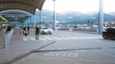 Bulanık yayalar ve araç modern havaalanı terminali yakınında, kapalı yürüyüş yolunun altında cam cepheli, yoğun ulaşım merkezi atmosferi taşır açık hava bokeh etkisi ile