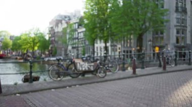 Bulanık bisikletler, Amsterdam kanallarına karşı sanatsal bir şehir sahnesi oluşturuyor. Hollanda 'da ağaçlar ve tarihi mimari yapılar var..