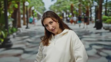 Güneşli bir şehir caddesinde neşeli bir şekilde gezinen bir kadın. Arka planda yürüyen insanlar kentsel, açık hava titreşimlerini güzel bir şekilde canlı bir şekilde yakaladılar..