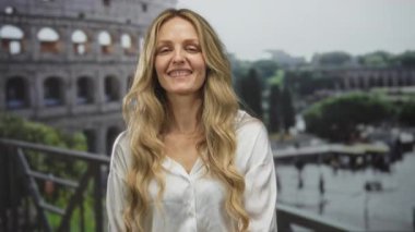 Roma 'da Roma Kolezyumu' nun yanında gülümseyen genç sarışın kadın Avrupa seyahatleri ve tarihi mimari sergiliyor..