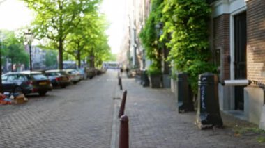 Amsterdam 'daki bulanık sokak manzarası park halindeki arabaların, yeşil ağaçların ve yumuşak Bokeh' te yakalanan şehir mimarisinin olduğu sakin bir şehir bölgesini gösteriyor..