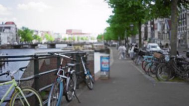 Bulanık bisikletler ve yeşil ağaçlarla dolu bir kanalda yaşayan insanlar ve Hollanda manzarası sergilenen tarihi binalar..