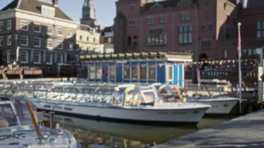 Amsterdam 'da klasik mimarisi ve güneşli atmosferi olan odaksız kanalların yanında duran adam.