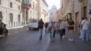 Tarihi Roma 'da dar kaldırım taşı caddelerinde yürüyen bulanık insanlar, odağını kaybetmiş mimari, bokeh ve güneş ışığı açık havada gölgeler bırakıyor..