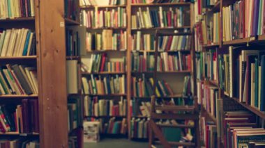 Kitaplıklar sessiz, bulanık bir kütüphane ortamında ve kapalı bir ortamda çeşitli kitaplarla dolu..