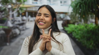 Kendine güvenen kadın elleri entrika çeviren Latin kökenli genç güler yüzlü balıkçı yaka yaka, oyuncu entrika ifadesini çağrıştırıyor..