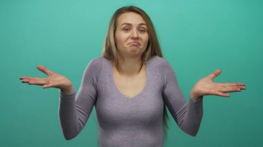 Yeşil arka planda omuz silkerek kafa karışıklığını ifade eden bir kadın, kararsızlık ya da belirsizliği işaret ediyor..