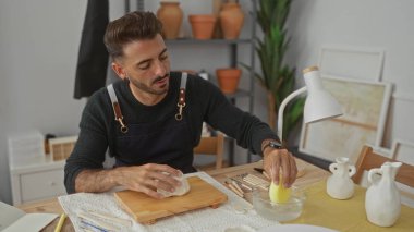 Stüdyoda beyaz çamuru çıplak elle şekillendiren İspanyol genç adam. Konsantrasyon yaratıcılığı..