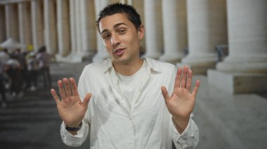 Gündüz vakti çevrede gezen eski bir kasabanın arka planında köşe yazıları olan sıradan giyinmiş İspanyol genç bir adam.