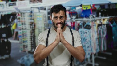 Beyaz gömlekli ve pantolon askısı takmış İspanyol bir adam renkli giyim ve aksesuarlarla dolu kalabalık bir sokakta minnettarlığını ifade ediyor..