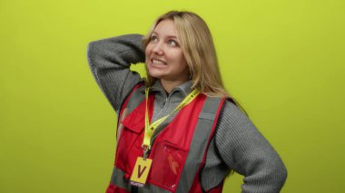 Kırmızı yelek giyen genç sarışın kadın mavi arka plan duvarına karşı duruyor, elleri kafasında duygularını gösteriyor..
