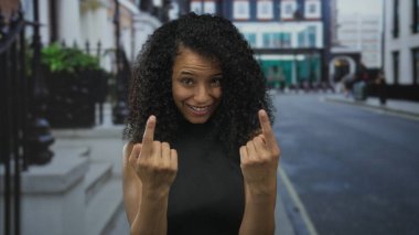 Genç İspanyol kadın sessiz şehir caddesinde iki eliyle işaret ediyor; dostça selamlaşma daveti.