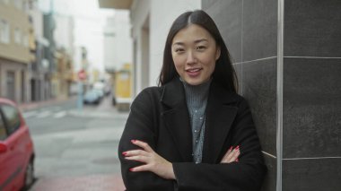 Şehir caddesinde kolları çapraz duran kadın şehir ortamında kendine güvenini ve tarzını gösteriyor..