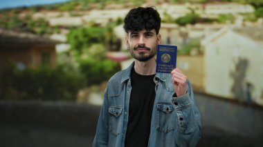 Belarus pasaportlu bir adam günlük kot pantolonla şehir merkezinde bulanık şehir manzarasına karşı kimlik ve seyahat hazırlığı sergiliyor..