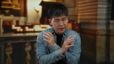 Tutkuyla kapalı alanda el kol hareketi yapan genç bir adam, dingin bir kilise geçmişine sahip, yoğun bir tartışma ya da vaaz verilmesini öneriyor..