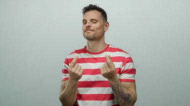 Genç adam, izleyiciyle iletişim kurarken özgüvenini ve çekiciliğini ifade ederek izole beyaz arka planda para hareketi yapıyor..