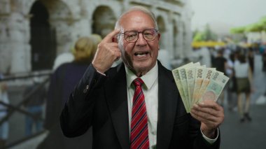 Takım elbiseli son sınıf öğrencisi elinde Czech Koruna banknotları Roma Kolezyum Caddesi 'nin yakınındaki açık havada el kol hareketleri yapıyor..